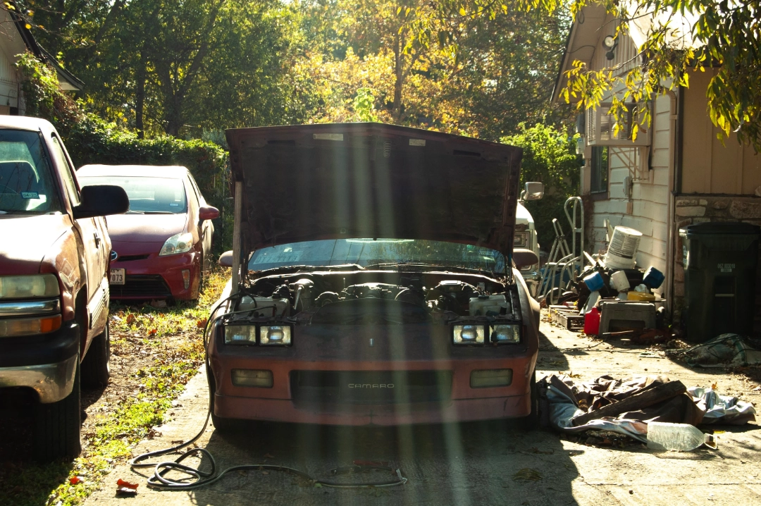 An old Chevrolet Camaro with its hood up.